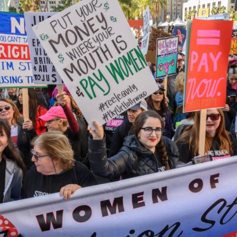 People marching while holding signs and a banner