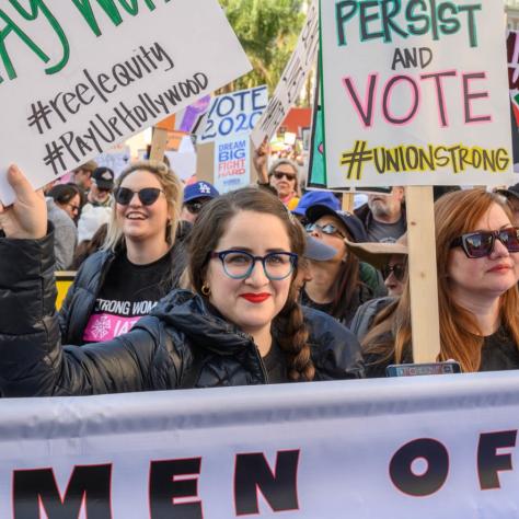 People marching while holding signs and a banner
