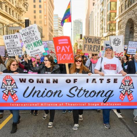 People marching while holding signs and a banner