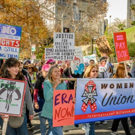 People marching while holding signs and a banner