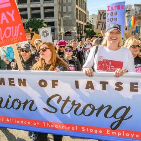 People marching while holding signs and a banner