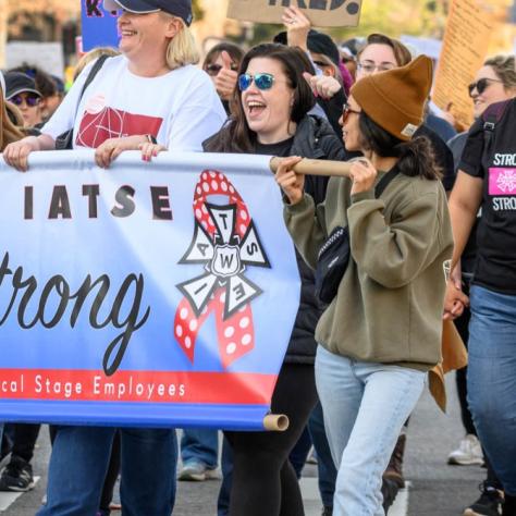 People marching while holding signs and a banner