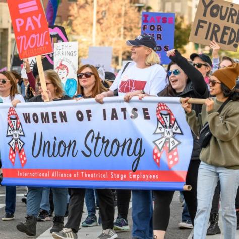 People marching while holding signs and a banner