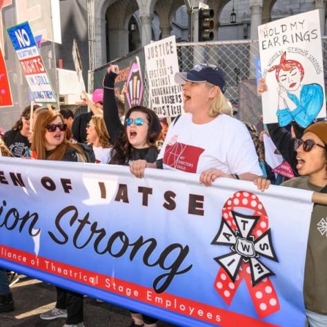 People marching while holding signs and a banner