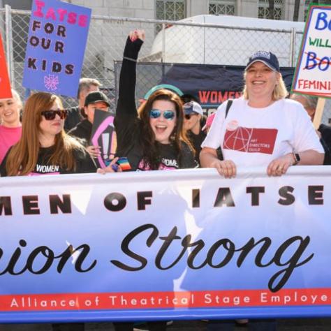 People marching while holding signs and a banner