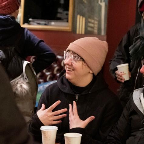 People wearing cold weather clothes drinking coffee indoors