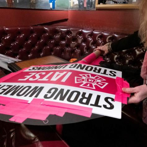 Women taping a sign to another sign