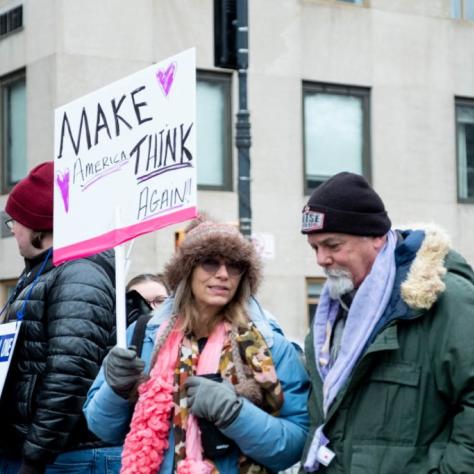 Woman holding sign chats with man while marching