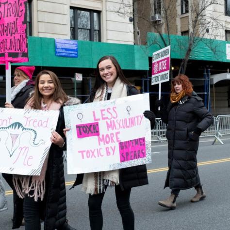 Women holding their signs pose for a photo