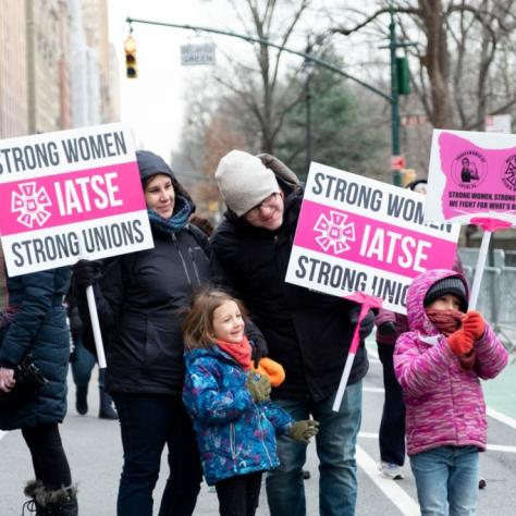 People and two kids holding signs