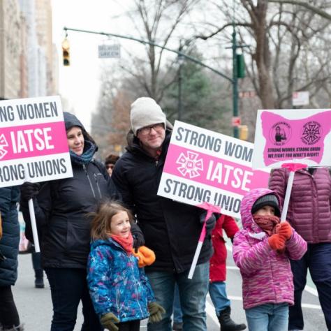 People and two kids holding signs