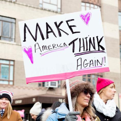 Woman holding a sign that reads "MAKE AMERICA THINK AGAIN!!"
