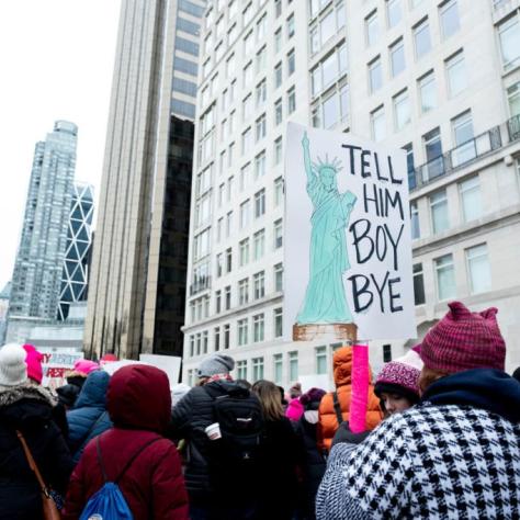 Woman holding sign that reads "TELL HIM BOY BYE"