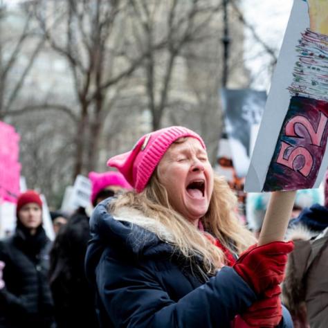 Woman holding sign while yelling