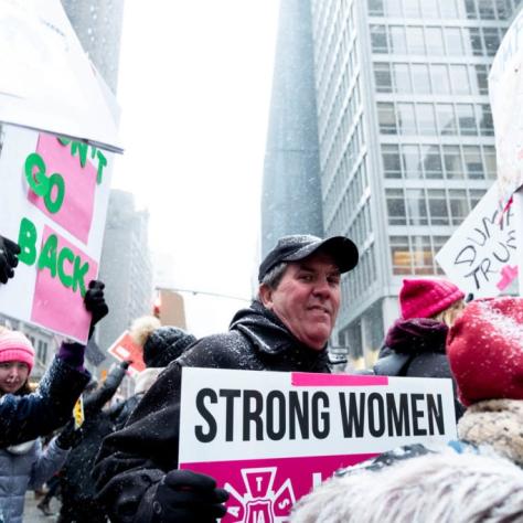 People marching while holding signs with snow falling