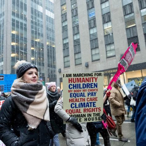People marching while holding signs with snow falling