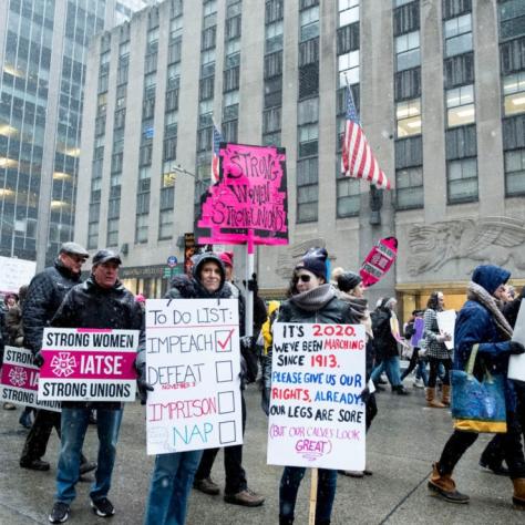 People marching while holding signs with snow falling