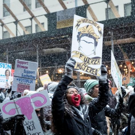 People marching while holding signs with snow falling