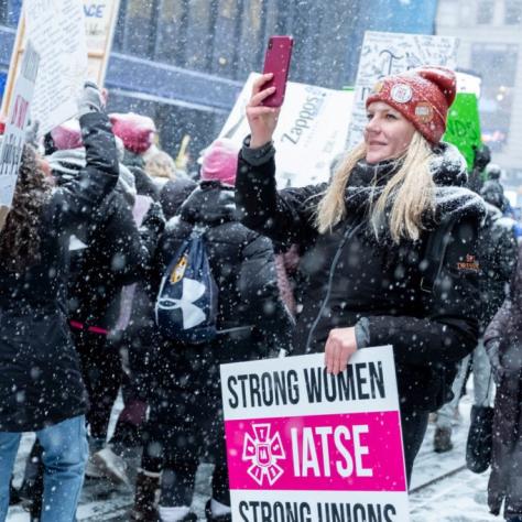 People marching while holding signs with snow falling