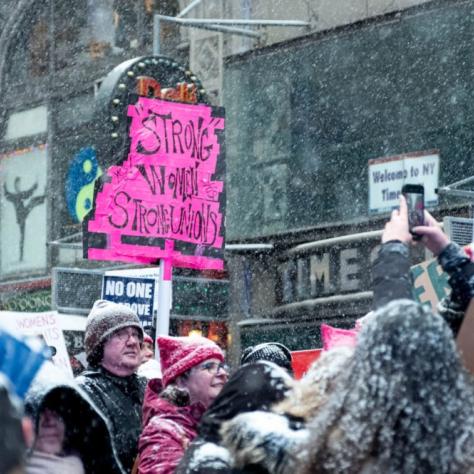 People marching while holding signs with snow falling