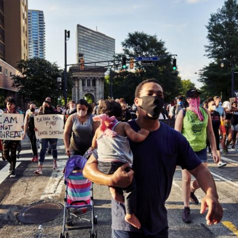 Man holds young child while marching in BLM protest
