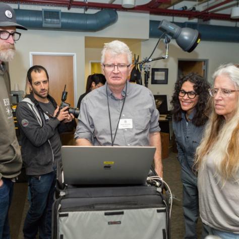 Man at a computer shows a group of people something