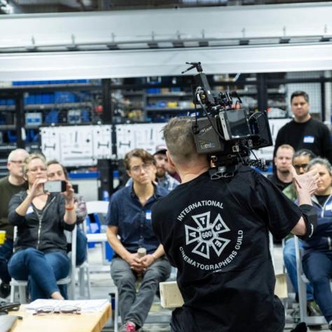 Man with camera demonstrates to students