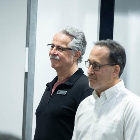 Two men stand and listen