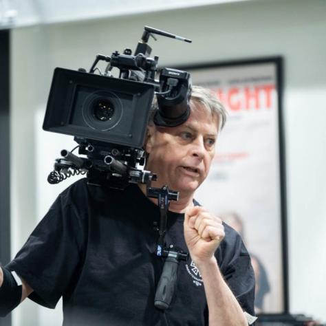 Man with camera demonstrates to students