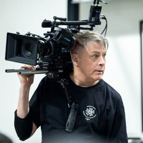Man with camera demonstrates to students