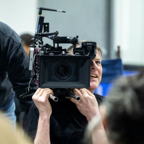 Man with camera demonstrates to students