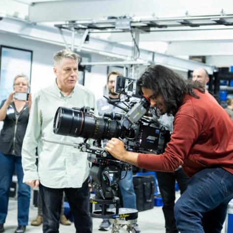 Man with camera demonstrates to students
