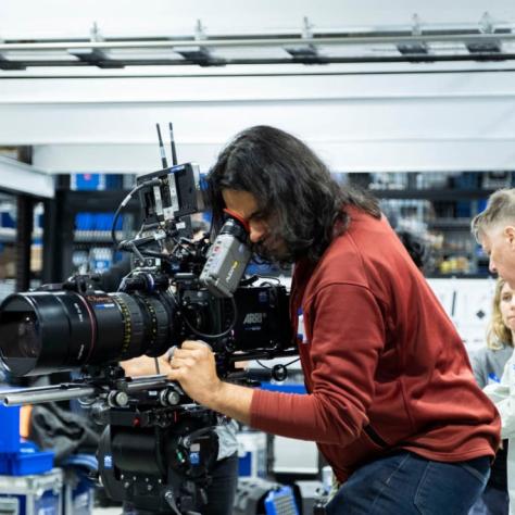 Man with camera demonstrates to students