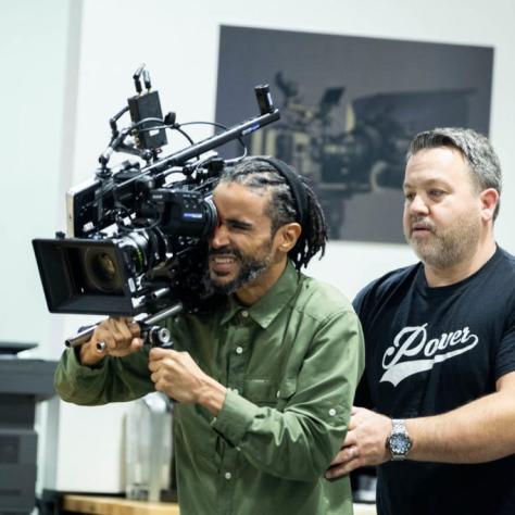 Man with camera demonstrates to students