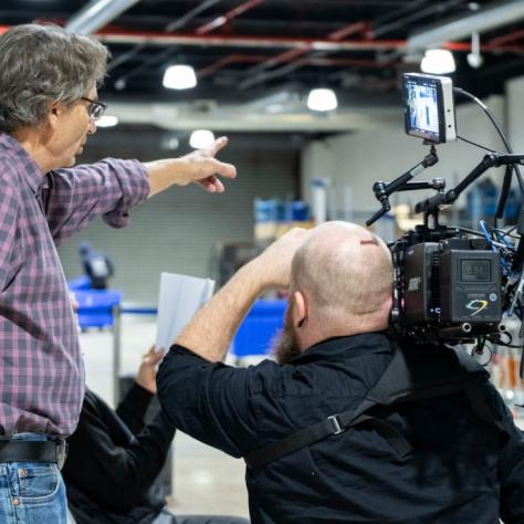 Man with camera demonstrates to students