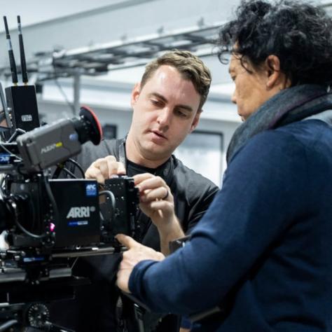 Two men adjust settings on the camera