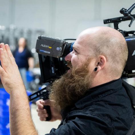 Man with camera demonstrates to students