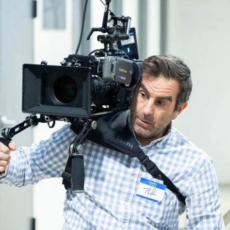 Man with camera demonstrates to students