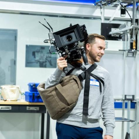 Man with camera demonstrates to students
