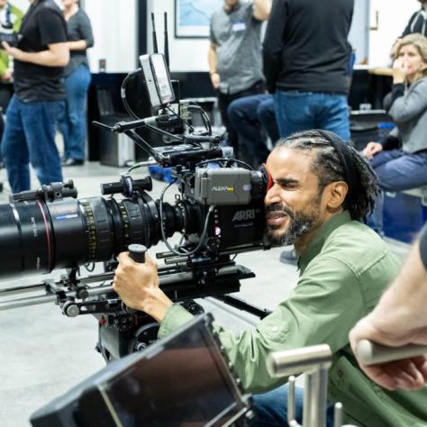 Man with camera demonstrates to students