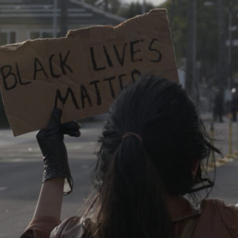 Person holding up a sign that reads "BLACK LIVES MATTER"